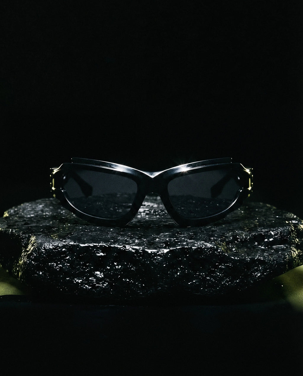 SCIROCCO — Y2K wraparound sunglasses still life on volcanic rock at night