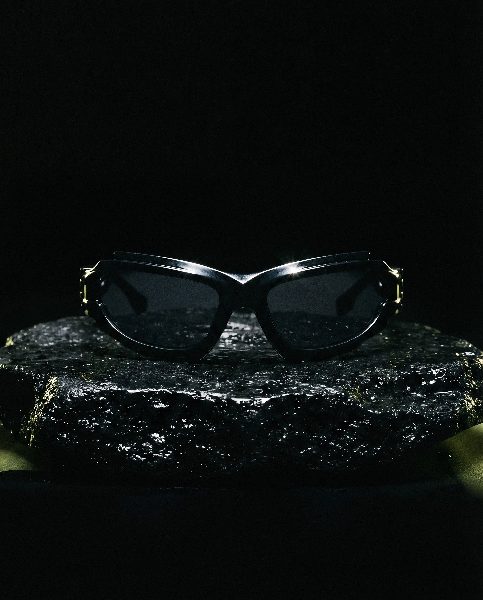 SCIROCCO — Y2K wraparound sunglasses still life on volcanic rock at night